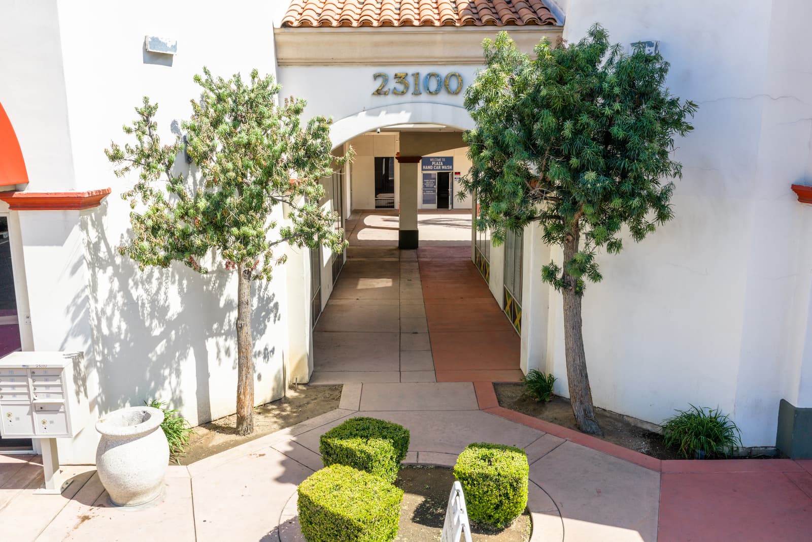 Arched entry to the 23100 building at Plaza Del Sol, with a landscaped courtyard walkway leading in