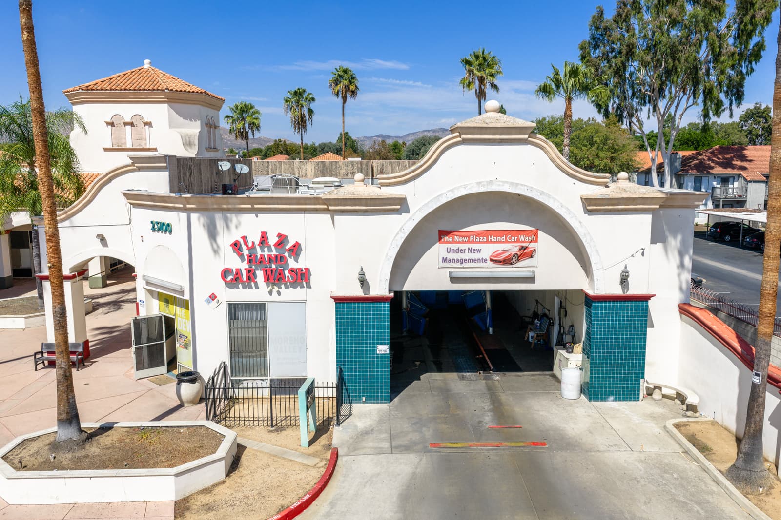 Plaza Hand Car Wash entrance: the arched wash tunnel at the 23100 building with the tile-roofed tower behind