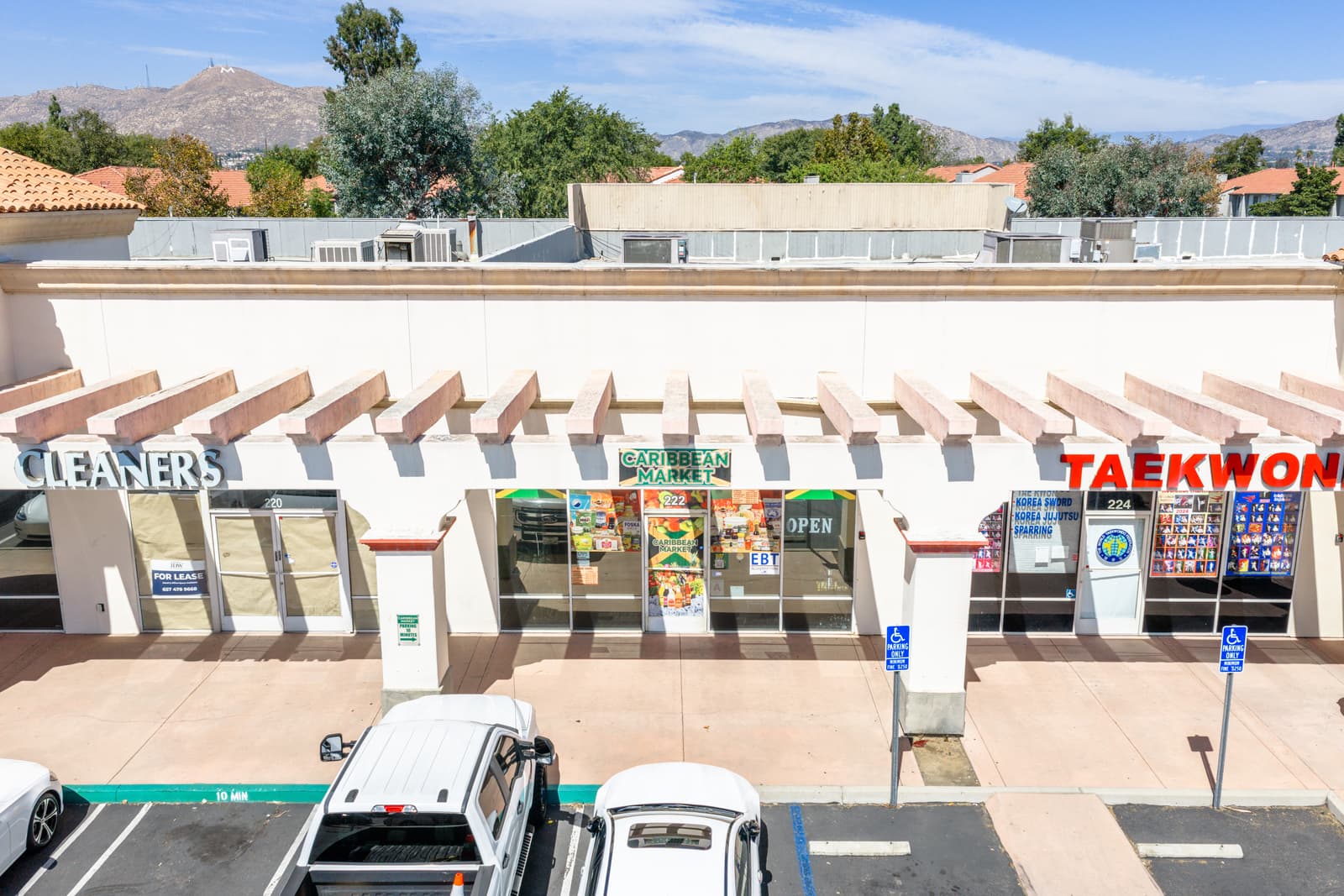 Caribbean Market, cleaners, and taekwondo storefronts along the Plaza Del Sol arcade