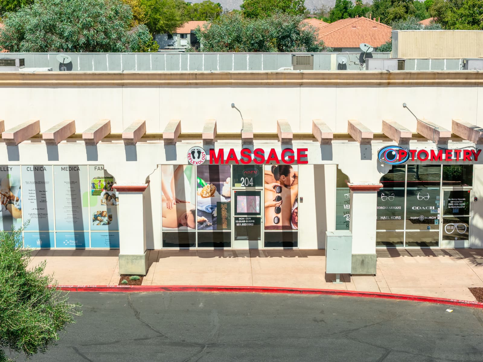 Massage and optometry storefronts along the covered arcade at Plaza Del Sol