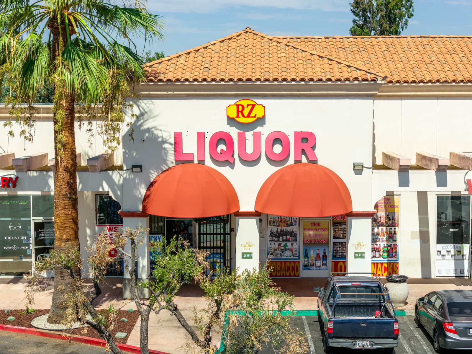 RZ Liquor storefront at Plaza Del Sol under two red awnings and the tile roof