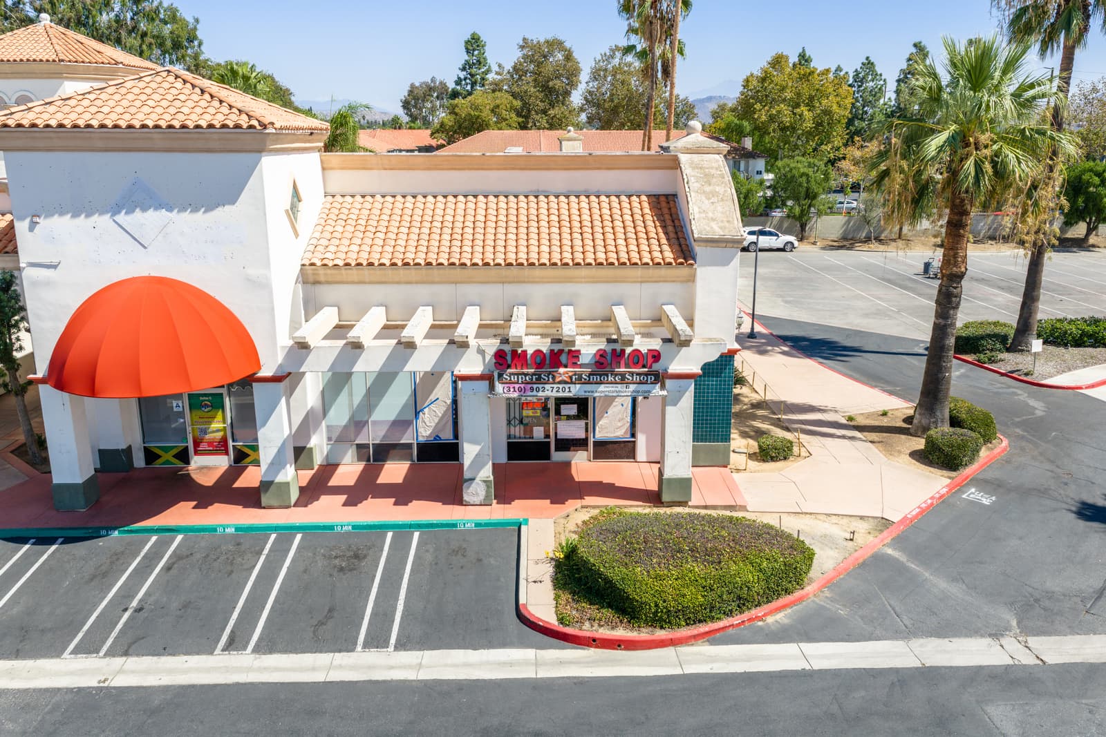Smoke shop pad building at Plaza Del Sol with its red awning and pergola